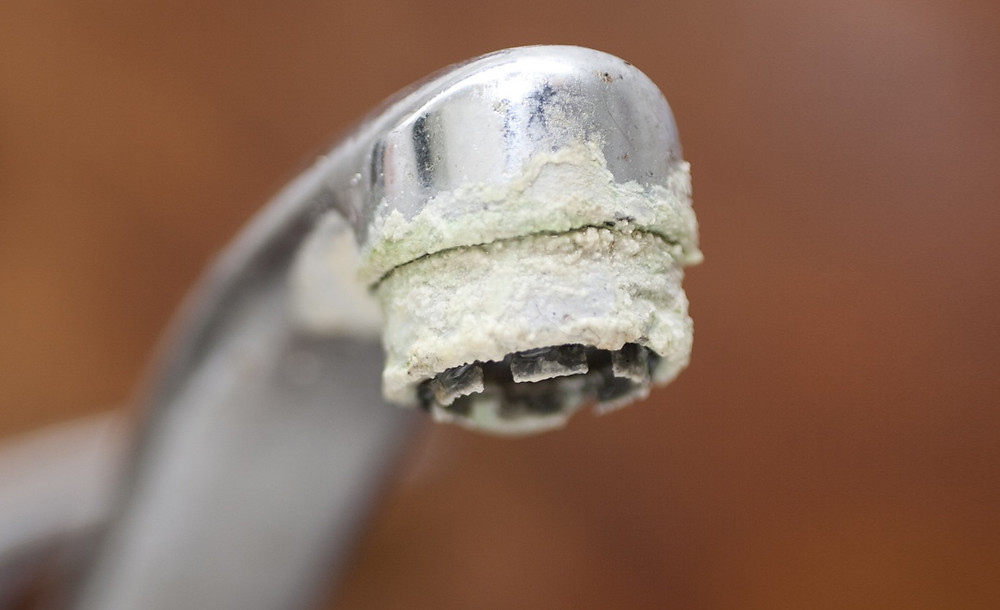 Close-up of white mineral scale around a faucet.